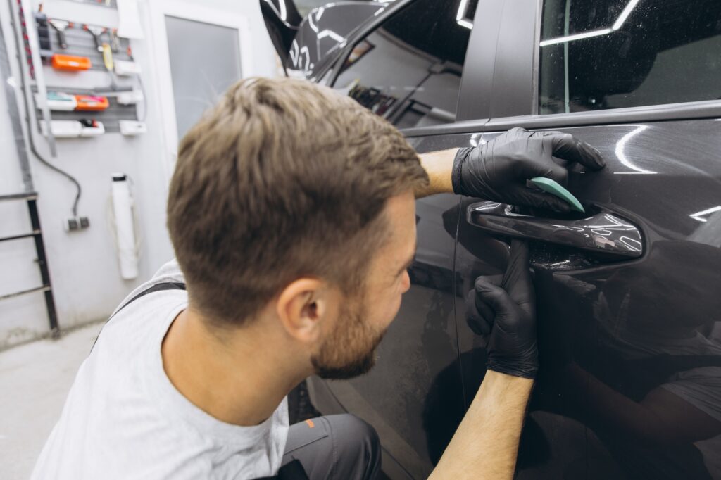 Car wrapping specialist putting vinyl foil or film on car.